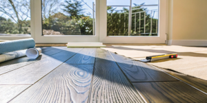 Waterproof vinyl flooring installation with tools and new planks on a prepared subfloor.